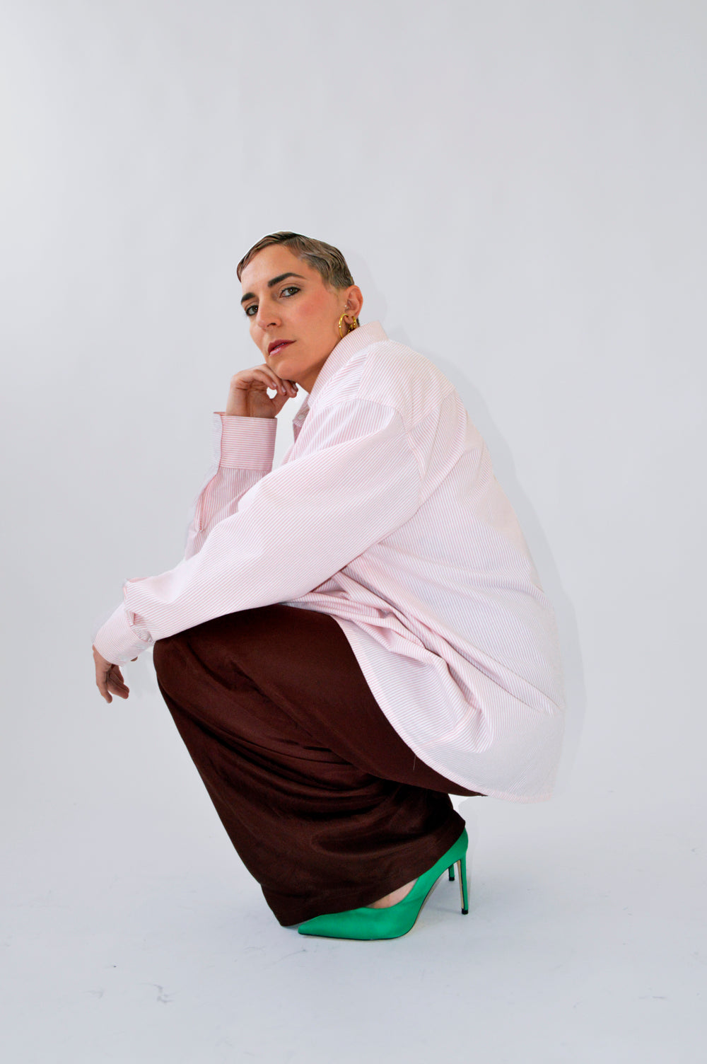 Modèle accroupie, portant la CHEMISE TOC TOC rayée rose et blanc et le PANTALON TOC TOC fluide marron.