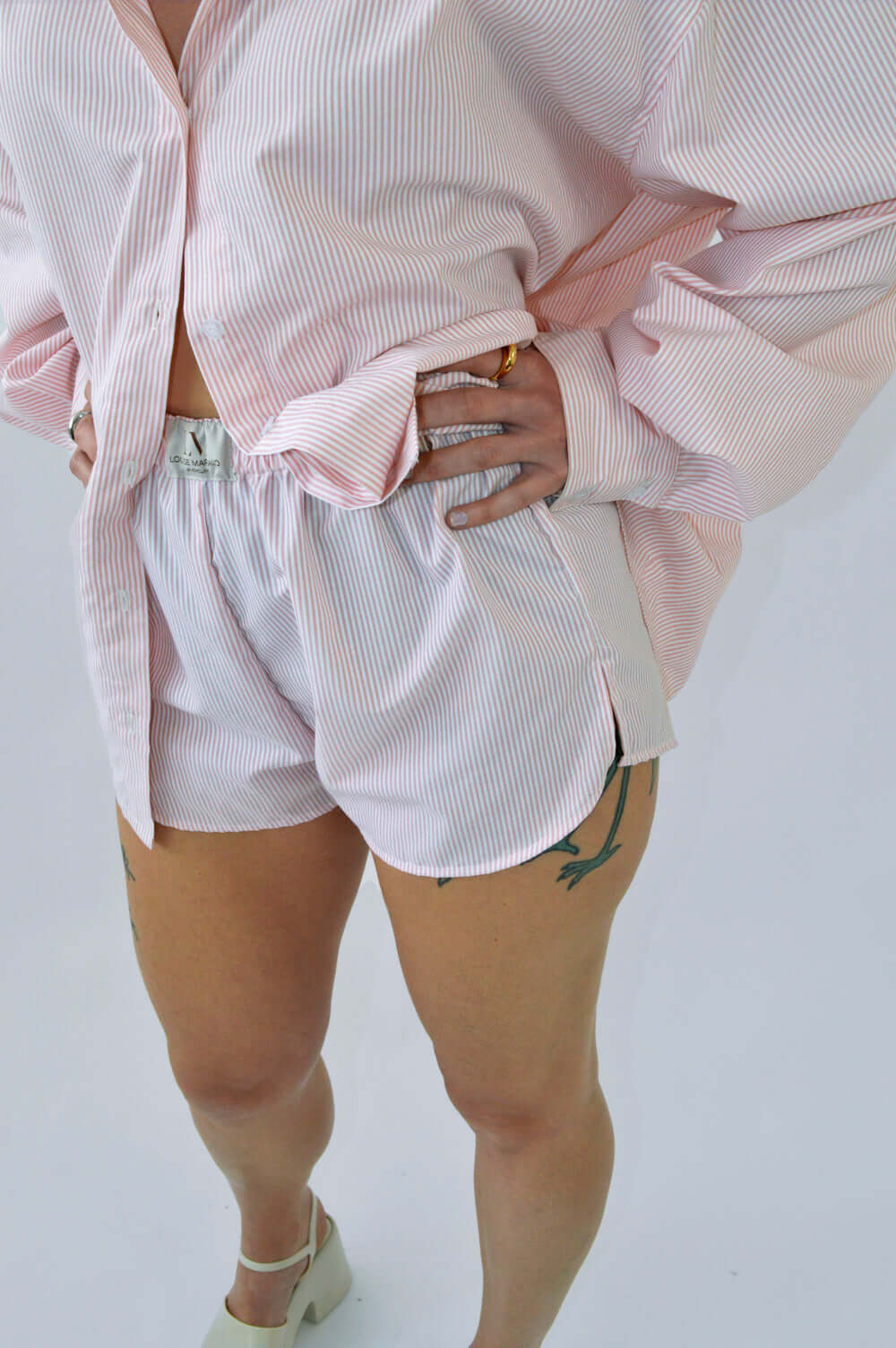 Femme portant le SHORT BLOOM rayé rose en coton, coupe boxer à taille élastique, assorti à la CHEMISE TOC TOC ROSE ample pour un look confortable et élégant.
