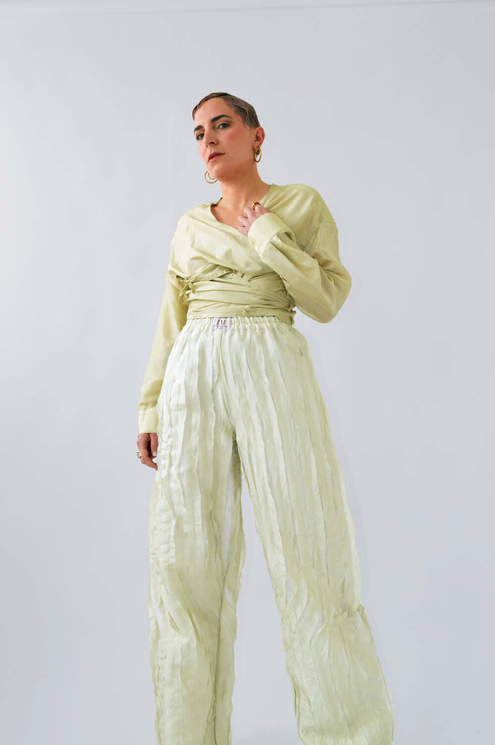 Vue contre-plongée d’une femme, avec le PANTALON TCHAC fluide en soie citron pastel.