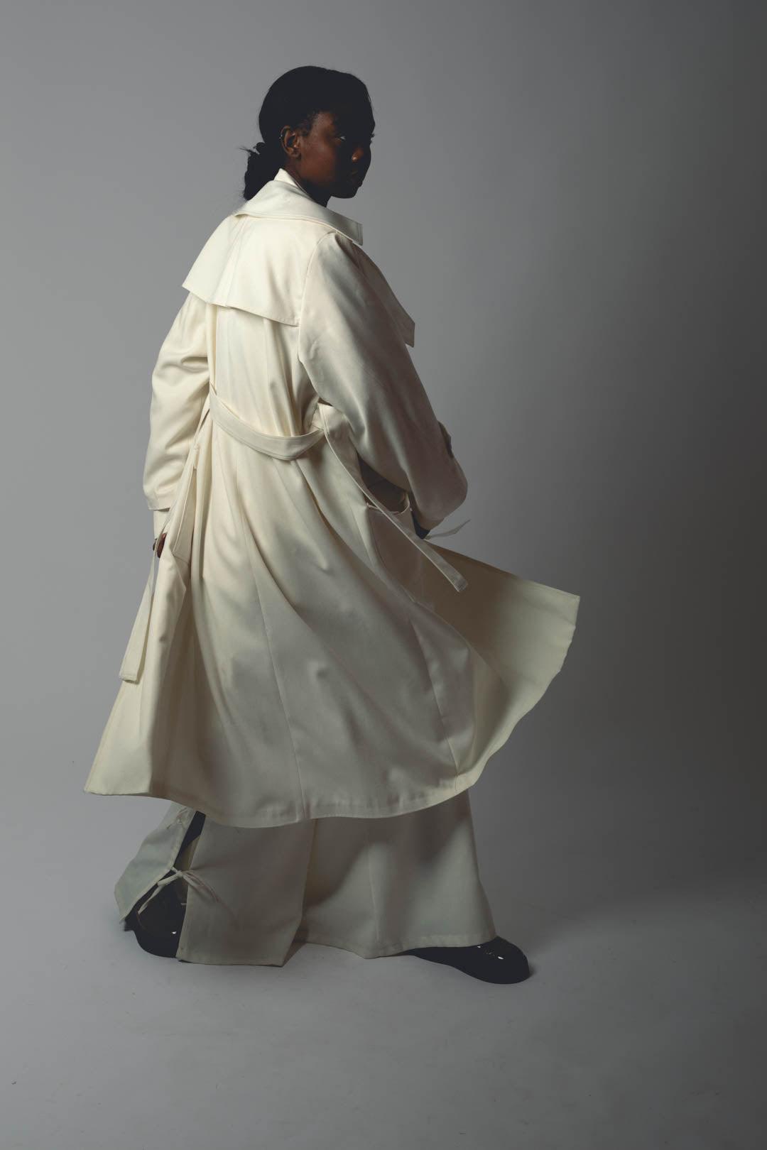 Femme portant le TRENCH OGIVE, détail dos, bavolet dos, ceinture, longueur mollet.