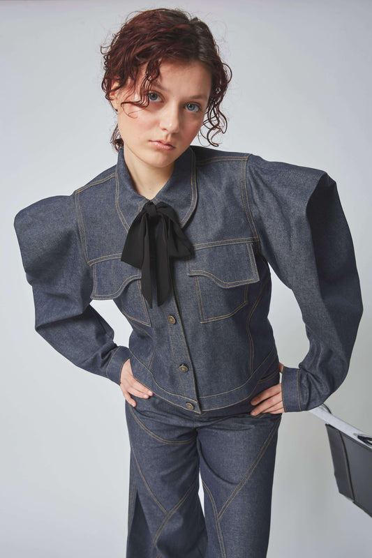 Femme portant la VESTE SONORA, pièce en jean ajustée, manches bouffantes, poches plaquées. 100% coton.