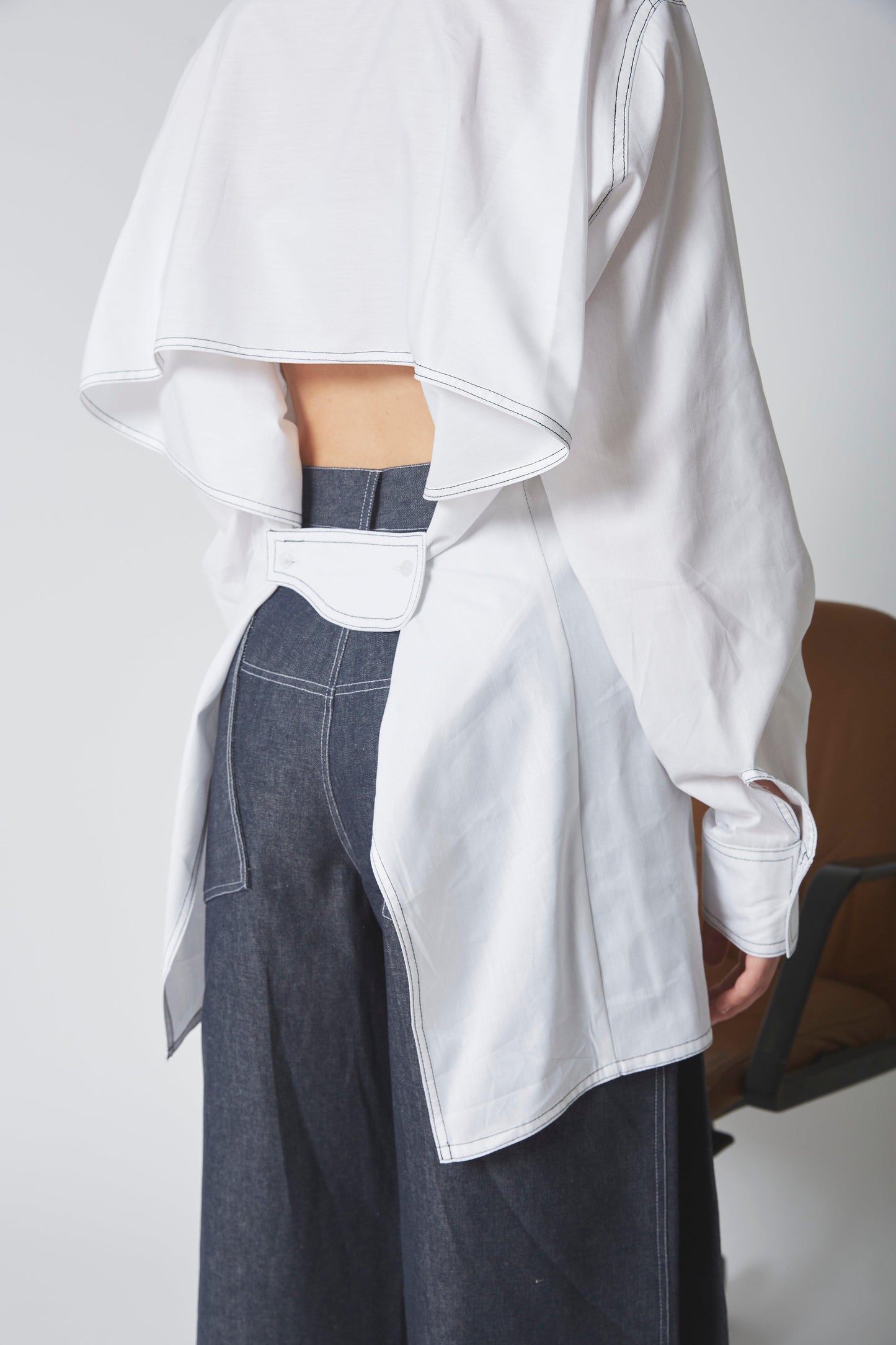 Femme portant la CHEMISE VOLUTE, 100% coton blanc, drapé dos, bride ajustable dos, volume.