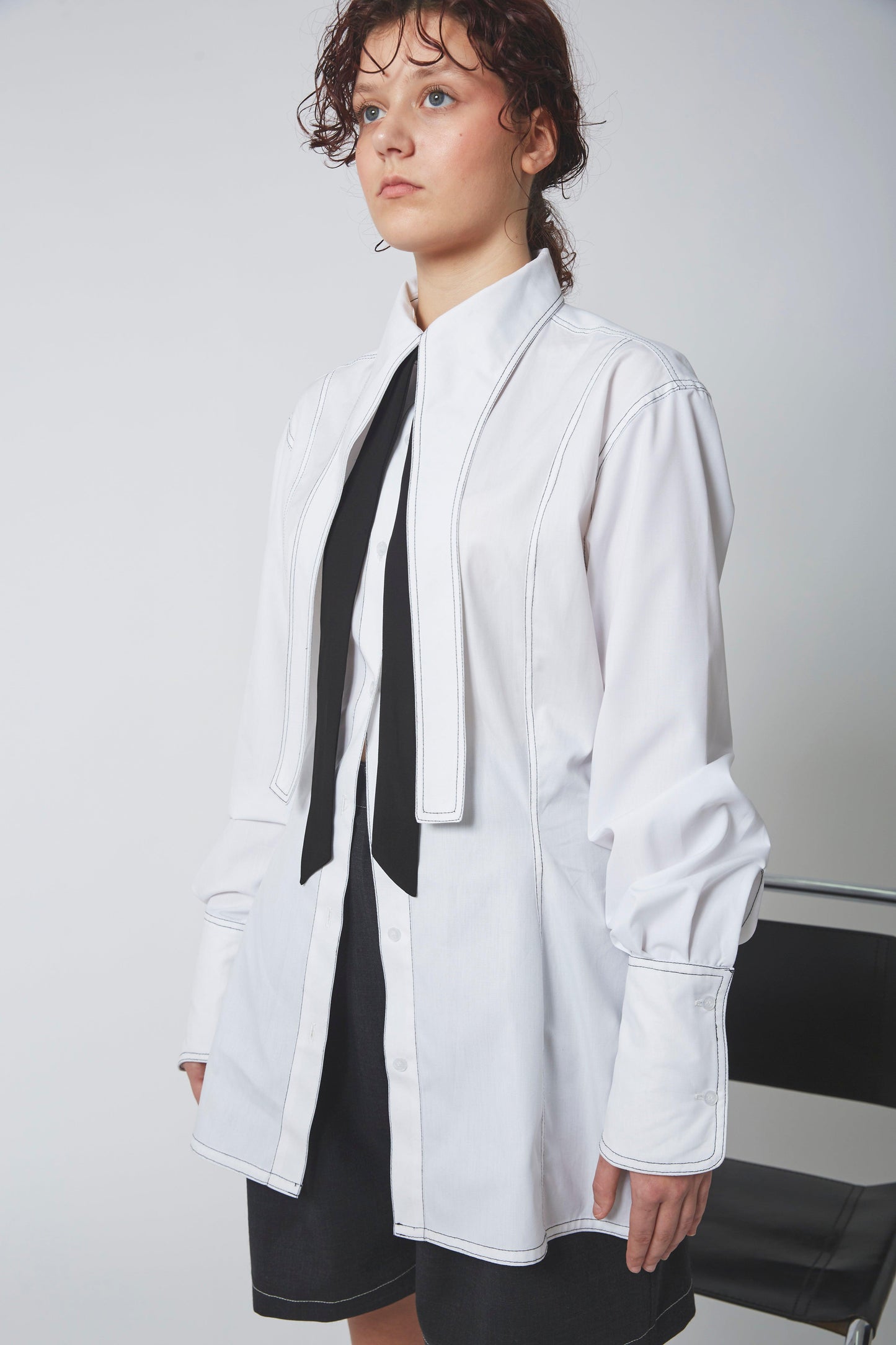 Femme portant la CHEMISE LIGNE FUYANTE, surpiqûres noires, découpes poitrine et taille.