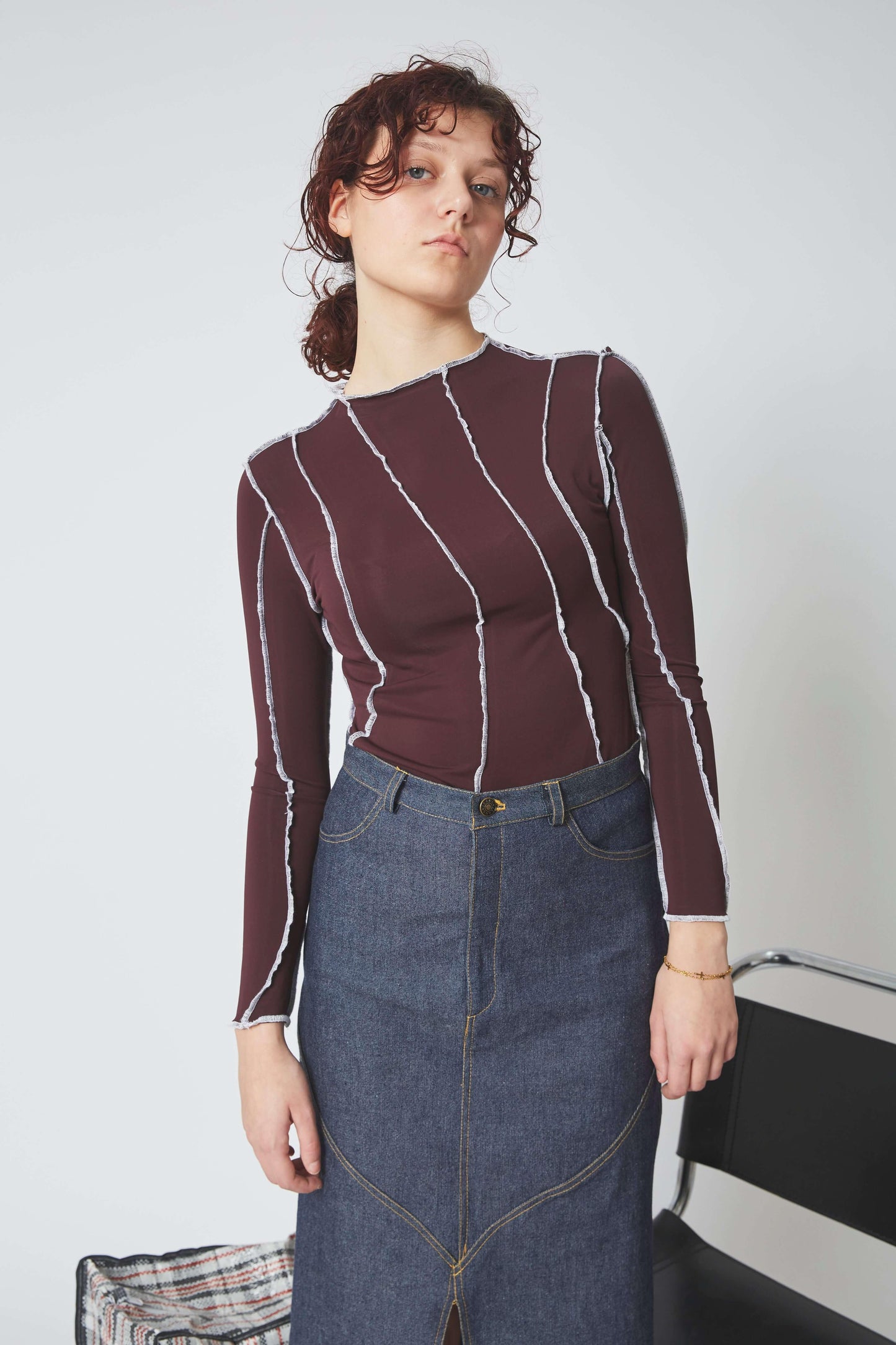 Femme portant le TOP SURJET AUBERGINE en lycra, surpiqûres blanches, manches longues et moulant.