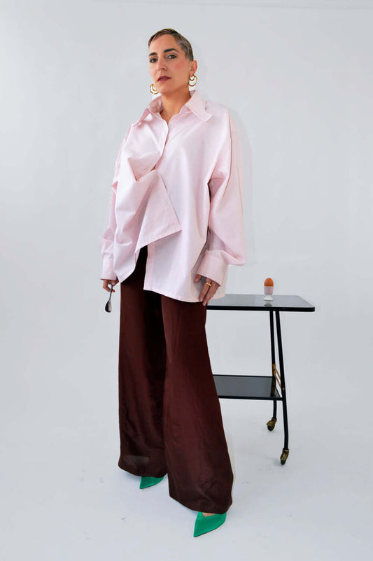 Femme portant le PANTALON BLOOM fluide en soie marron avec une chemise rose, affichant un look chic et décontracté.