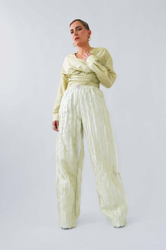 Femme en contre-plongée portant le pantalon fluide TCHAC en soie citron pastel avec blouse assortie, pour un look élégant et dynamique.