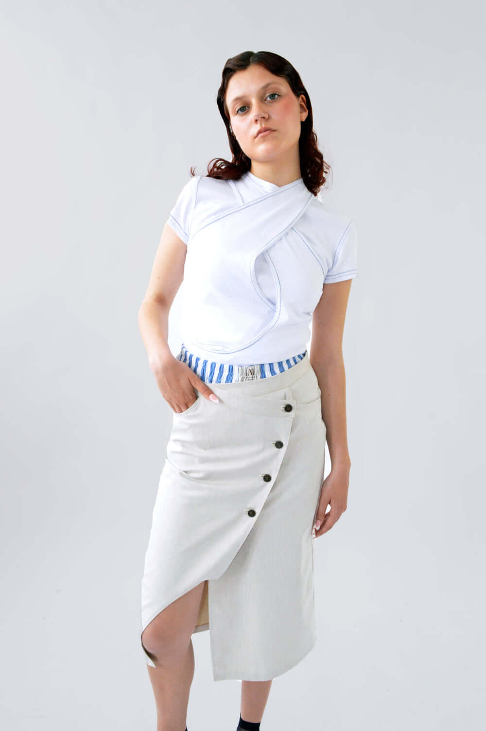 Femme debout portant le SHORT BLOOM rayé bleu et blanc en coton, légèrement visible sous une jupe claire fendue, associé à un top CLIC CLAC BLANC. 