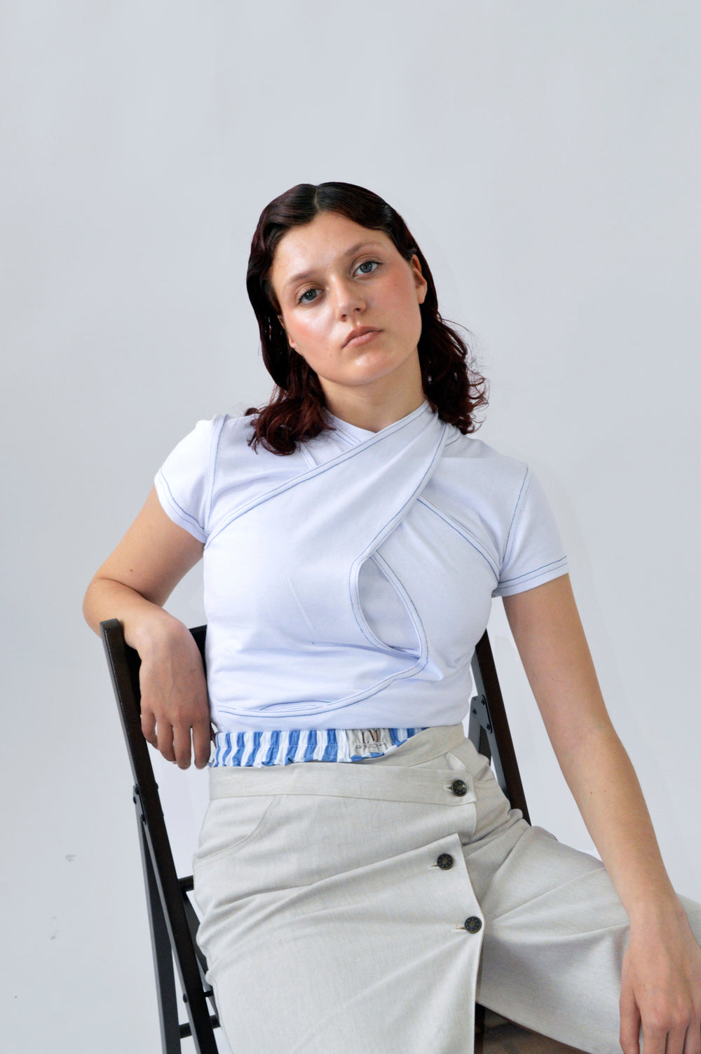 Femme portant l’ensemble CLIC CLAC TOP composé d’un t-shirt moulant et d’un débardeur blanc croisé à surpiqûres bleues, dans une pose détendue.