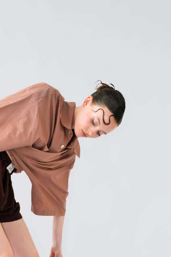 Femme portant la chemise PAF PAF marron et le SHORT BLOOM en soie aubergine marron, dans une pose dynamique sur fond clair.